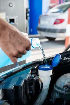 filling the tank of windshield washer fluid.