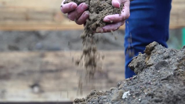 Sifting with hands and pouring dirt and sand at field