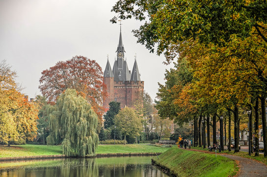 Zwolle, the Netherlands, November 11, 2019: view along the city's ramparts canal, lined with trees in autumn colors, towards historic Sassnepoort gate