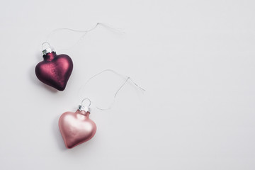Two Christmas decorations in the form of a pink and plum-colored heart with copy space on a white background