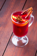 Glass of mulled wine and cinnamon sticks on wooden boards. Christmas mulled wine with orange...
