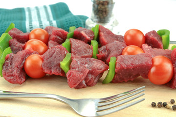 skewers of beef, pepper and raw tomato on a white background