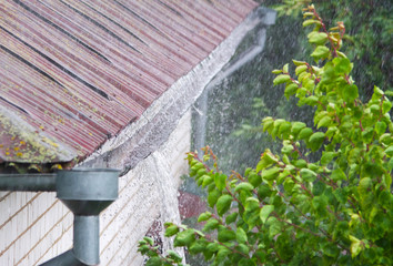 Closeup of leaking rain gutter overflowing with water during the rain