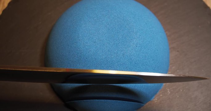 Blue kinetic sand in a round shape is cut by a sharp knife
