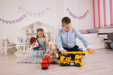 beautiful happy caucasian children playing in their room, boy playing with cars, girl playing with...