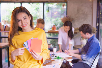 Beautiful woman showing and choosing designed color in front of meeting group 