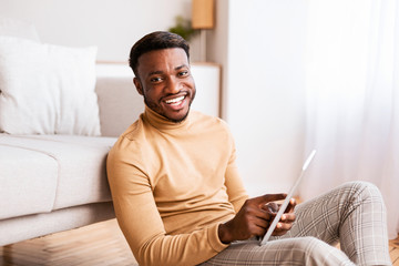 Black Guy Using Tablet Sitting On Floor At Home