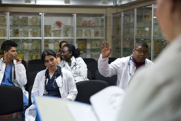 hospital, profession, people and medicine concept - group of happy doctors meeting and asking...