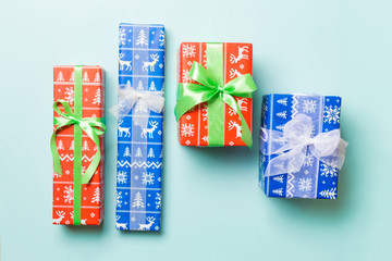 wrapped Christmas or other holiday handmade present in paper with white and green ribbon on blue background. Present box, decoration of gift on colored table, top view