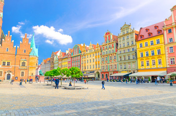 Row of colorful buildings with multicolored facade and Old Town Hall building on cobblestone Rynek...