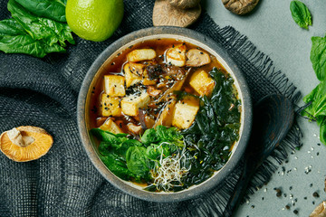 Fresh vegetarian miso soup with shiitake mushrooms, tofu cheese and seaweed on a gray cloth....