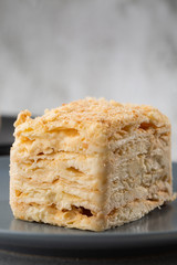 Piece of cake Napoleon on blue plate on marble background, close up view. Traditional millefeuille dessert with puff pastry and custard, copy space. Vertical photo. Photo for bakery menu.