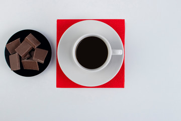 White cup of black coffee on a red napkin.