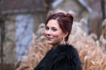Medium horizontal photo of pretty young woman with hair in bun smiling seductively and wearing faux...
