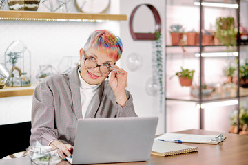 Gorgeous woman wearing glasses and blazer sit working on laptop. Business people concept