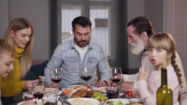Attractive happy different generation family enjoying dinner around the family feast
