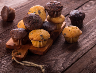 Assorted fresh delicious muffins on wooden background