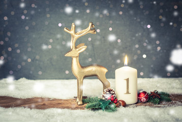 white, burning candle in winter landscape with fir and christmas decoration