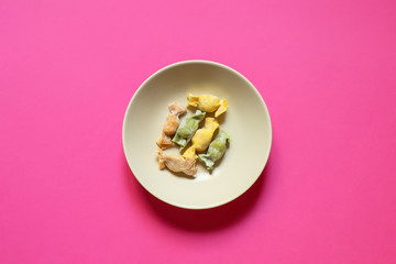 Stuffed Pasta with caramelle shape served in a cream bowl over a fuchsia background top view