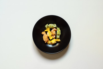 Stuffed Pasta with caramelle shape served in a black bowl over a white background