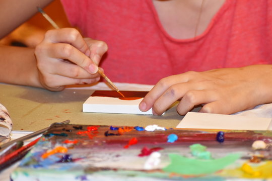 Girl draw a picture with paints. Brushes and artist's palette. Training in drawing.