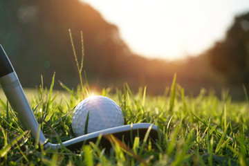 Verschwommener Golfschläger und Golfball hautnah auf der Wiese mit Sonnenuntergang. Golfball hautnah auf Golfplätzen in Thailand