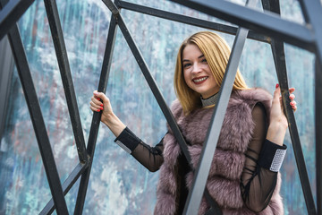 Urban portrait of young lady in fur coat. Woman in elegant dress posing on city street