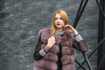Urban fashion. Portrait of fashion woman in fur coat posing on city street