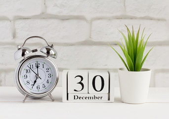 December, alarm clock and calendar on the table December 30 on a wooden calendar next to the clock