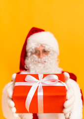 Christmas gift box with white bow in Santa's hands over orange