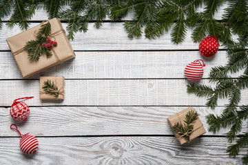 Christmas background with green fir branches and gift boxes on white planks