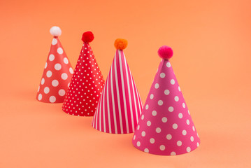 Colorful birthday caps on orange background.