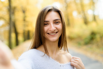 Naklejka premium Female portrait. Young woman in casual wear posing in autumn forest with yellow leaves