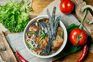 Vegetarian bowl with ramen soup, shiitake mushrooms, soy meat on a wooden tray in a composition with fresh vegetables. Healthy food.