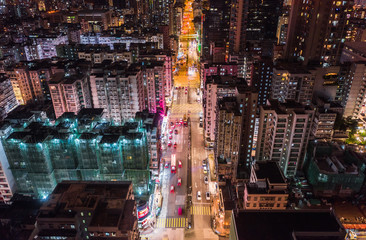 Fototapeta na wymiar Car, taxi, and bus traffic on road intersection at night in Hong Kong downtown district, drone aerial top view. Street commuter, Asia city life, or public transportation concept