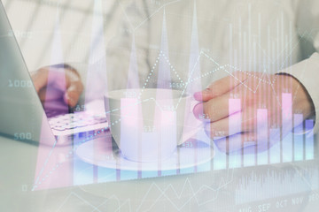 Double exposure of graph with man typing on computer in office on background. Concept of hard work.