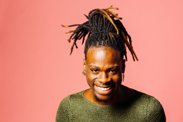 Portrait of a happy, smiling  young man in with cool dreadlocks hairstyle looking at camera, isolated on pink. - Powered by Adobe