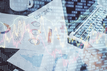 Double exposure of stock graph with businessman typing on computer in office on background. Concept of hard work.