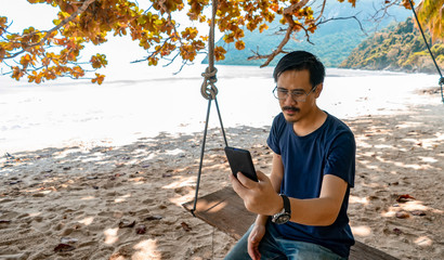 A man use the phone and sitting on a swing At the private beach in asia the tropical forest © nuttapon