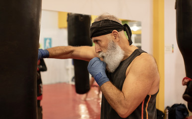 Senior male boxer ready to fight. Senior boxer in gloves boxing in gym