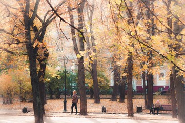 A woman with a dog  walking in autumn park