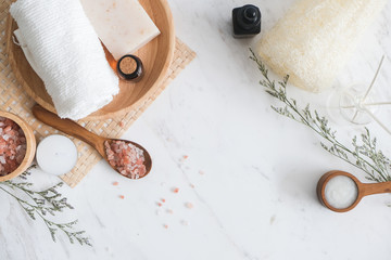 Flat lay spa products with copy space. Sea salt in bowl, towels, stone, aroma oil in bottles and...