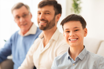 Fototapeta premium Boy With Father And Grandfather Sitting On Couch At Home