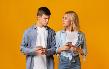 Jealous boyfriend looking at girlfriend's cellphone, checking her messages