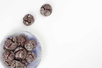Chocolate crinkle cookies in blue plate, white background. Christmas, recipe concept. Top view, flat lay, copy space