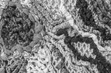 Fragment of the panel, connected from heterogeneous and multi-colored woolen threads, non-repeatable pattern, close-up, black-and-white image.