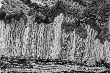Fragment of the panel, connected from heterogeneous and multi-colored woolen threads, non-repeatable pattern, close-up, black-and-white image.
