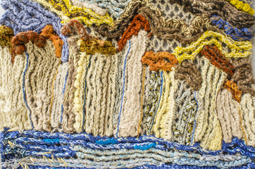 Fragment of a panel, connected from heterogeneous and multi-colored woolen threads, non-repeatable pattern, close-up.