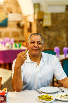 Middle Eastern Senior Man Eating In A Cafe Restarant.