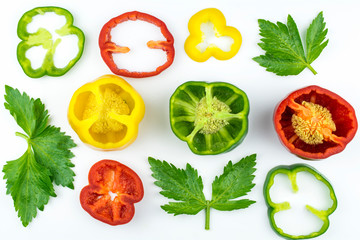 Celery leaves, sliced ​​in circles sweet pepper of red, yellow and green color isolated on a white background.